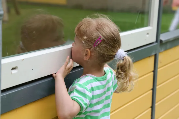 Meisje kijkt door raam Elzenhoek foto Baalderborggroep