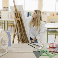 Blonde young woman sitting workshop painting easel
