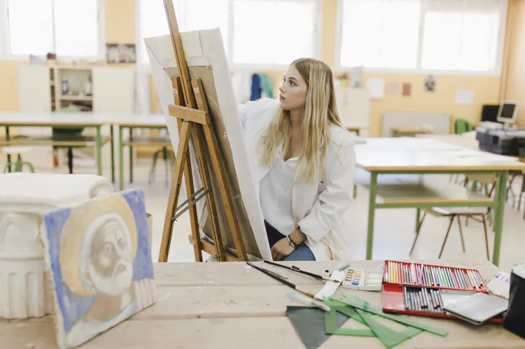 Blonde young woman sitting workshop painting easel