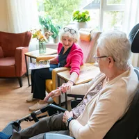 Oudere dame op bezoek bij bewoner in rolstoel - foto Niels Zomer